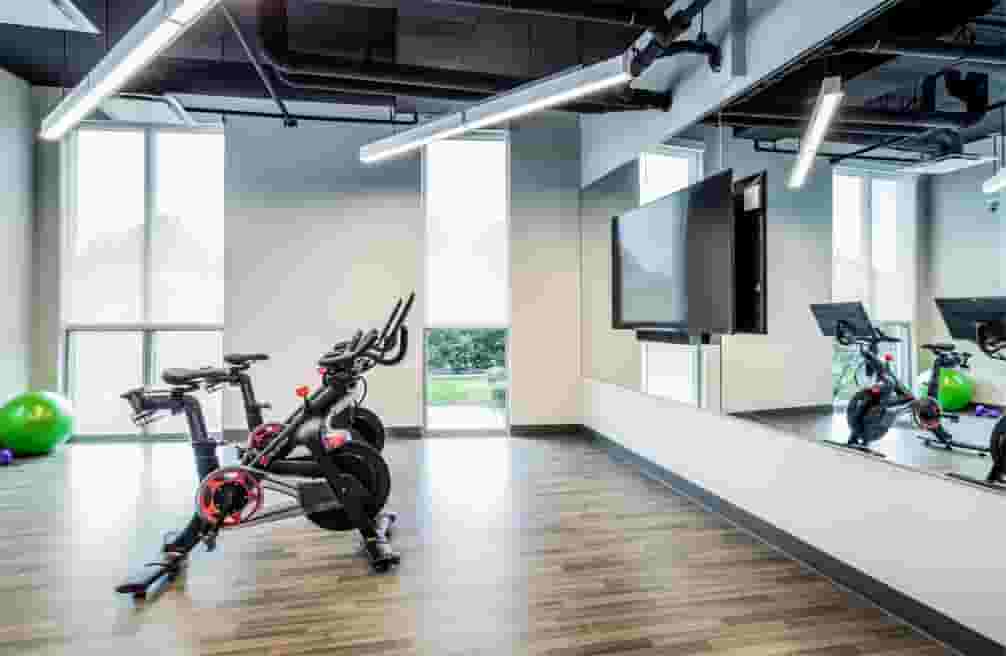 Pelotons and yoga space with mirror wall and mounted TV in the Yoga Studio