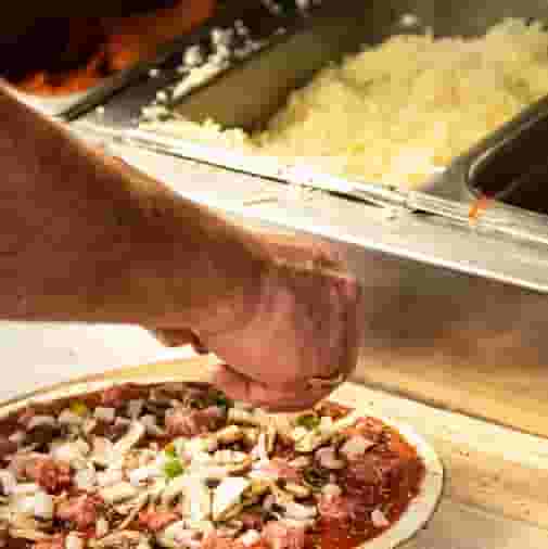 Cook making a pizza at Sam's Pizza