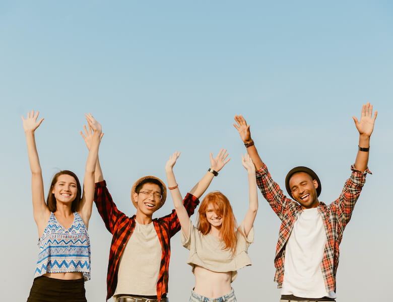 ECU students laughing with their arms in air while posing for photo together